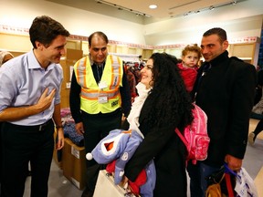 Syrian refugees are greeted by Canada's Prime Minister Justin Trudeau (L) on their arrival from Beirut at the Toronto Pearson International Airport in Mississauga, Ontario, Canada December 11, 2015. After months of promises and weeks of preparation, the first Canadian government planeload of Syrian refugees landed in Toronto on Thursday, aboard a military aircraft met by Prime Minister Justin Trudeau.  REUTERS/Mark Blinch TPX IMAGES OF THE DAY