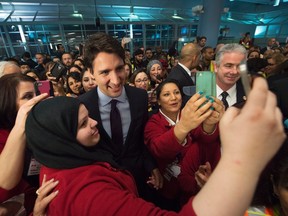 Prime Minister Justin Trudeau, centre, poses for selfies with workers before he greets refugees from Syria at Pearson International airport, in Toronto, on Dec. 10, 2015. (THE CANADIAN PRESS/Nathan Denette)