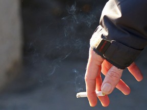 TIM MILLER/THE INTELLIGENCER
A man holds a smoking cigarette near Belleville city hall.