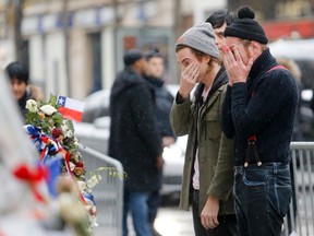 Jacques Brinon/The Associated Press
Members of the band Eagles of Death Metal, Jesse Hughes, right, and Julian Dorio pay their respects on Tuesday to 89 victims who died in a Nov. 13 attack at the Bataclan concert hall in Paris. Members of the California rock band are back at the ravaged Paris theatre where they survived a massacre by Islamic extremist suicide bombers.
