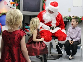 Morgan Vanluven, foreground, isn't so sure about Santa as he speaks to her sister Maci and brother Xavier at the Community Christmas dinner hosted by The Salvation Army Rideau Heights Corps in Kingston, Ont. on Saturday December 12, 2015. Steph Crosier/Kingston Whig-Standard/Postmedia Network