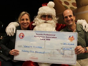 Variety Village CEO Karen Stintz, with a little help from Santa Claus, accepts a $25,000 donation from Toronto Professional Firefighters Association president Frank Ramagnano on Dec. 12, 2015. (Shawn Jeffords/Toronto Sun)