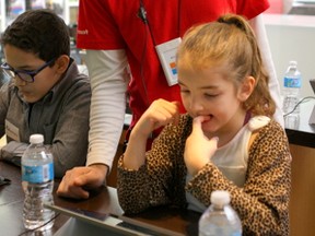 Amir Khiabani helps Bashira James, 7, learn to code during the Hour of Code event at  the Microsoft store in West Edmonton Mall on Sunday, Dec. 13, 2015. (CLAIRE THEOBALD/ Edmonton Sun)
