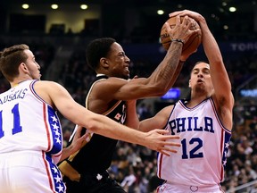 Toronto Raptors' DeMar DeRozan, centre, is fouled on the way to the net by Philadelphia 76ers' T.J. McConnell (12)as Nik Stauskas looks on during first half NBA basketball action in Toronto, Sunday, Dec. 13, 2015. THE CANADIAN PRESS/Frank Gunn
