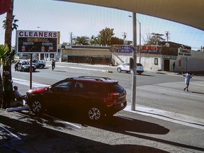 In this image made from security video footage provided by the Los Angeles County Sheriff, a man, right, walks with a gun in his hand Saturday, Dec. 12, 2015 in Lynwood, Calif. Two deputies fired 33 bullets at the man after he refused to drop the gun and walked across a busy street to a filling station where a family was pumping gas, homicide Cpt. Steven Katz said. He died at the scene Saturday morning. Authorities released the video Sunday in response to questions about why they continued to fire on the man after he fell to the pavement. (Los Angeles County Sheriff via AP)