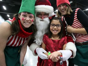 Savannah Couterielle gets close to Santa and his elves at the Big Brothers, Big Sisters Christmas party at Edmonton Northlands in Edmonton, Alberta on December 13, 2015. ( Perry Mah/Edmonton Sun/Postmedia Network)