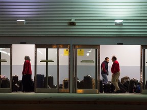 Workers help newly arrived Syrian refugees load their luggage onto busses at Pearson International airport, in Toronto, on Friday, Dec. 11, 2015. THE CANADIAN PRESS/Nathan Denette