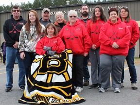 Leanne Babcock, in Boston Bruins blanket, her daughter Kaitlyn, left, and their family at the Frontenac Community Arena in Godfrey on Saturday. Leanne is the mother of Travis Babcock, 12, who was killed in a motor vehicle collision in November. (Steph Crosier/The Whig-Standard)