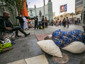 In this Dec. 9, 2015 file photo, "Star Wars" fans Deuce Wayne, from Virginia, left, and Larry Ross from La Crescenta, Calif., right, rest while waiting in line up outside the TCL Chinese Theater Imax for the "Star Wars: The Force Awakens" premiere in Los Angeles. (AP Photo/Damian Dovarganes, File)