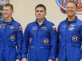 The International Space Station (ISS) crew (L to R), Timothy Peake of Britain, Yuri Malenchenko of Russia and Timothy Kopra of the U.S., pose behind a glass wall after a news conference at Baikonur cosmodrome, Kazakhstan, Dec. 14, 2015.  REUTERS/Shamil Zhumatov