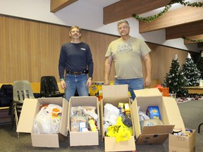 Greg Young, right, of the Vermilion Ridge Riders, presents food collected at the Snowmobile Expo to Derek Collins of the Vermilion Food Bank.
