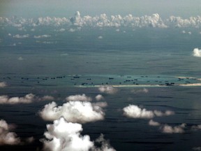In this Monday, May 11, 2015, file photo, this aerial photo taken through a glass window of a military plane shows China's alleged on-going reclamation of Mischief Reef in the Spratly Islands in the South China Sea. (Ritchie B. Tongo/Pool Photo via AP, File)