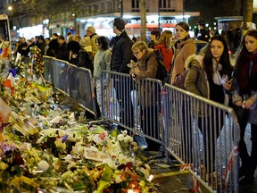 People look at the floral tributes placed to honour the victims of the Paris attacks across from the Bataclan concert hall in Paris Saturday, Dec. 12, 2015.  (AP Photo/Matt Dunham)