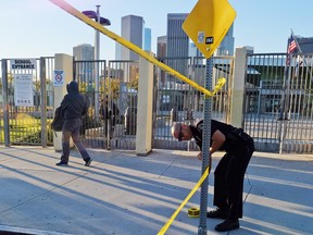 A police officer puts up yellow tape to close the school, as a student walks past, outside of Edward Roybal High School in Los Angeles, on Tuesday morning, Dec. 15, 2015. (AP Photo/Richard Vogel)