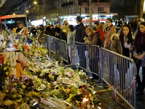 People look at the floral tributes placed to honour the victims of the Paris attacks across from the Bataclan concert hall in Paris Saturday, Dec. 12, 2015. (AP/Matt Dunham)