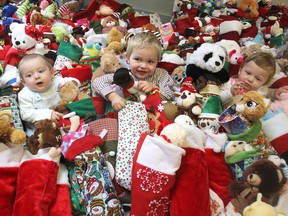 Liam Down-Elliott, eight months old, left, Noah Down-Elliott, 3, and Isabella Evans-Sweet, 10 months old, sit in the middle of more than 225 Christmas stockings at the Kingston Community Health Centres in Kingston on Tuesday. The stockings were donated to children in the centres' programs. (Michael Lea/The Whig-Standard)