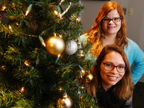 Luke Hendry/The Intelligencer
Loyalist College students Ashley Watson, top, and Alicia McDonld stand behind a Christmas tree in Belleville Wednesday. Working with Volunteer and Information Quinte, they helped to bring 20 decorated trees to area families thanks to local donors.