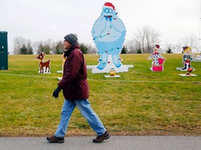 Luke Hendry/The Intelligencer
Claude Cairns walks past the holiday display in Jane Forrester Park in Belleville Wednesday. Environment Canada forecasters predict a green Christmas for the area, due in part to El Nino, the warming of equatorial waters in the Pacific Ocean.
