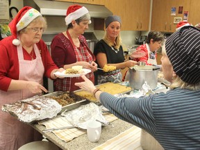Volunteers with Lunch By George begin serving a turkey Christmas meal on Wednesday for its clients at St. George’s hall. More than 100 people showed up for the feast. (Michael Lea/The Whig-Standard)