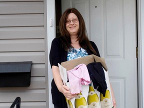 Rebecca Sawyer, in front of her home, holds one of the dozens of boxes of material donations that she hopes to pass along to refugee families. (Jolson Lim/For The Whig-Standard)