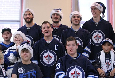Anthony Peluso, Connor Hellebuyck, Alexander Burmistrov, and Tyler Myers (back row from left) of the Winnipeg Jets take a group picture following a visit to the Rehabilitation Centre for Children on Wellington Crescent in Winnipeg on Wed., Dec. 16, 2015. Paul Postma also took part. Kevin King/Winnipeg Sun/Postmedia Network