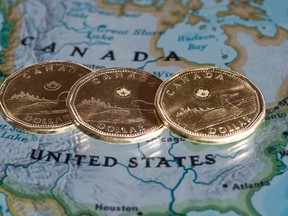 Loonies are displayed on a map of North America, in Montreal, Que., in this Jan. 9, 2014 file photo. (THE CANADIAN PRESS/Paul Chiasson)