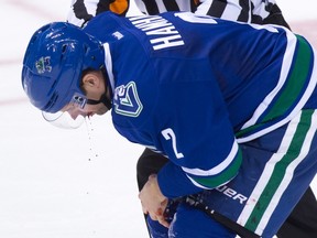 Canucks defenceman Dan Hamhuis is helped off the ice by referee Ian Walsh after being struck in the mouth by the puck during third period NHL action against the Rangers in Vancouver on Dec. 9, 2015. Hamhuis wears a visor, but it didn't protect his jaw when a puck hit his face, requiring hospitalization. (Darryl Dyck/THE CANADIAN PRESS)