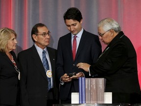 Canada's Prime Minister Justin Trudeau (2nd R) is presented with an copy the Truth and Reconciliation Commission's final report by Commissioner Marie Wilson (L), Commissioner Chief Wilton Littlechild (2nd L) and Justice Murray Sinclair in Ottawa, Canada, December 15, 2015. Trudeau pledged to work toward full reconciliation with Canadian Aboriginals on Tuesday as he accepted a final report on the abuses of the government's now-defunct system of residential schools for indigenous children. REUTERS/Chris Wattle