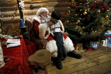 Actor John Field, dressed as Santa Claus, holds six-year-old Jack at a grotto at the Wetland Centre in London, Britain, Dec. 5, 2015. REUTERS/Stefan Wermuth