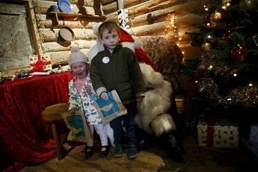 Two-year-old Eliza and her four-year-old brother James pose for a picture with actor John Field, dressed as Santa Claus, at a Christmas grotto at the Wetland Centre in London, Britain, Dec. 5, 2015. REUTERS/Stefan Wermuth
