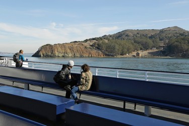 In this photo taken Thursday, Nov. 5, 2015, passengers on the Tiburon ferry look out at Angel Island near Tiburon, Calif. Angel Island was once the home to an immigration station and military forts. (AP Photo/Eric Risberg)