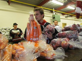 Jordan Fogarty joined teammates from the Sarnia Legionnaires passing along bags of apples, carrots and potatoes to members of Local 663, and volunteers, who delivered 100 food and toy hampers for the Salvation Army on Friday December 18, 2015 in Sarnia, Ont. Paul Morden/Sarnia Observer/Postmedia Network