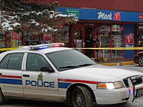 An Edmonton Police Service vehicle blocks the parking lot an an officer walks out of the Mac's, the scene of a robbery-homicide at 32 Ave. and 82 St., in Edmonton on Friday Dec. 18, 2015. Two people were killed in separate robberies in the early morning hours. Three suspects were taken into custody after a vehicle pursuit. Tom Braid/Edmonton Sun/Postmedia Network.