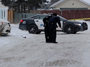 Two Edmonton Police Service members record tire tracks in the alley behind a Mac's, the scene of a robbery-homicide at 32 Ave. and 82 St., in Edmonton on Friday Dec. 18, 2015. Two people were killed in separate robberies in the early morning hours. Three suspects were taken into custody after a vehicle pursuit. Tom Braid/Edmonton Sun/Postmedia Network.