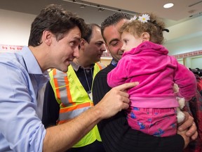 Prime Minister Justin Trudeau greets 16-month-old Madeleine Jamkossian, right, and her father Kevork Jamkossian, refugees fleeing the Syrian civil war, during their arrival at Pearson airport in Toronto on Friday, Dec. 11, 2015. (THE CANADIAN PRESS/Nathan Denette)