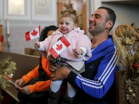 Syrian refugee Kevork Jamgochian holds his daughter Madlin at the St. Mary Armenian Apostolic Church during a welcome service at the Armenian Community Centre of Toronto in Toronto last week. (Mark Blinch/Reuters)