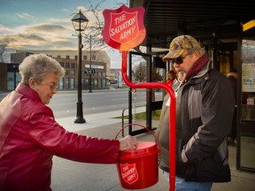A Kingston LCBO customer drops change in volunteer Glen Owen's Salvation Army Christmas kettle at the Princess Street LCBO on Friday. With Christmas less than a week away, the campaign still needs close to $130,000 to meet its goal. (Marc-Andre Cossette/The Whig-Standard)