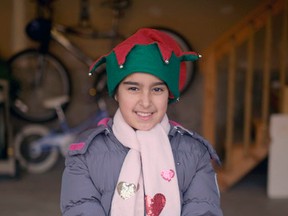 Nine-year-old Sarah Essaddam holds a donation box in the garage of her Draper Avenue home in Kingston that acted as a stage for her benefit concert for Syrian refugees last Saturday. (Jolson Lim/The Whig-Standard)
