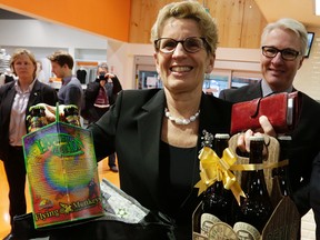 Premier Kathleen Wynne picks up some beer at Loblaw in Toronto on Dec. 15, 2015 as beer becomes available in some Ontario grocery stores. (Craig Robertson/Toronto Sun)