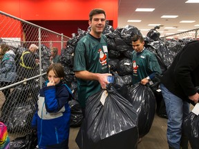 Mayor Don Iveson helps move bags of gifts during 630 CHED Santas Anonymous delivery weekend at Boonie Doon Mall in Edmonton, Alta., on Saturday December 19, 2015. The charity, through the work of volunteers, delivers Christmas gifts to less fortunate familes across the city. Ian Kucerak/Edmonton Sun/Postmedia Network