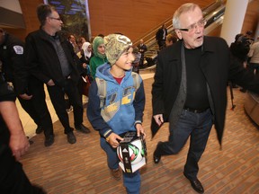 Ray Loewen greets members of the Daas family, on their way to collect  luggage in Winnipeg.  The family is a among a group of 17 refugees who arrived in Winnipeg from Syria, via Lebanon, and Toronto, Saturday, December 19, 2015.   (Sun/Postmedia Network)
