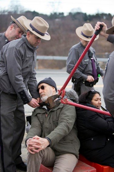 Police use bolt cutters to remove an interlocking device around James Cromwell's neck during a protest at a power plant that is under construction in Wawayanda, N.Y., Friday, Dec. 18, 2015. New York state police say the several protesters who were arrested blocked an entrance to the construction site at the Competitive Power Ventures power plant. (Erik Gliedman/Times Herald-Record via AP)