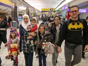 Syrian refugees dad Asiad and mom Nour walk through the Calgary International Airport to their new home in Canada in Calgary, Ab., on Friday December 18, 2015. (Mike Drew/Calgary Sun/Postmedia Network)