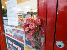 A note and a bouquet of flowers is seen on the door of the Mac's at 82 Street and 32 Avenue a day after a man was shot dead in an armed robbery in Edmonton, Alta., on Saturday December 19, 2015. Another man was killed by the same three suspects in a robbery at a Mac's at 108 Street and 61 Avenue. Ian Kucerak/Edmonton Sun/Postmedia Network