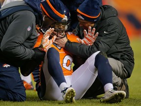 Strong safety David Bruton #30 of the Denver Broncos is attended to by trainers after a play that would force him out of the game with a reported concussion during a game against the Oakland Raiders at Sports Authority Field at Mile High on December 28, 2014 in Denver, Colorado.   Doug Pensinger/Getty Images/AFP