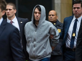 In this Dec. 17, 2015 file photo, Martin Shkreli, the former hedge fund manager under fire for buying a pharmaceutical company and ratcheting up the price of a life-saving drug, is escorted by law enforcement agents in New York after being taken into custody following a securities probe.  Shkreli  has resigned as the head of one of the companies he now runs, Turing Pharmaceuticals, on Friday, Dec. 18, 2015.(AP Photo/Craig Ruttle)