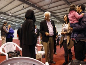 Minister of Immigration John McCallum, centre, talks to a Syrian family soon to be resettled in Canada, Sunday, Dec. 20, 2015, at an airport in Amman, Jordan. McCallum said the country’s resettlement program for Syrian refugees could double by the end of 2016. (AP Photo/Sam McNeil)