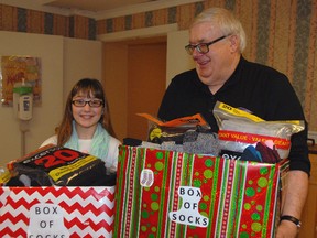 Eleven-year-old Lauren Martin, left, hands over 302 pairs of socks to Inn Out of the Cold program director Jim Nace Thursday afternoon. Lauren spearheaded a collection campaign at her school and in the community to help the local shelter.