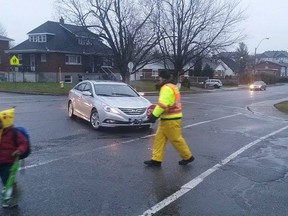 Crossing guard Claude Larose hops out of the way of a vehicle passing through the intersection of Cummings Ave. and Gardenvale Rd. on Thursday, Dec. 17, 2015 as his charges scamper to the corner in an incident captured by another parent. Larose says the incident, which he and a witness called a near miss, is not the first he's had, but this one was reported to Ottawa police. Cops say they are investigating. (Submitted image, Ottawa Sun / Postmedia Network