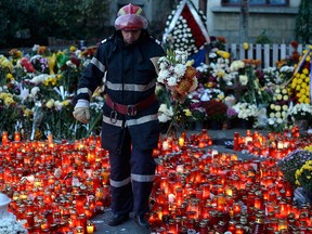 A fireman carries flowers as he walks between lit candles as thousands mourn the victims of a nightclub fire in Bucharest, Romania Nov. 1, 2015.  REUTERS/Inquam Photos/Octav Ganea